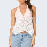Woman wearing a pink halter top with floral lace overlay and blue jeans